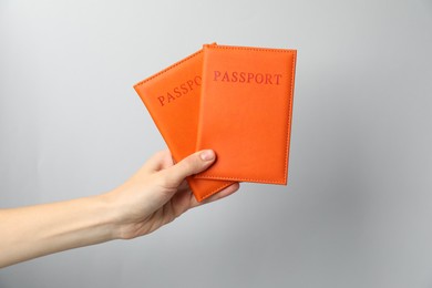 Photo of Woman holding passports in bright covers on grey background, closeup