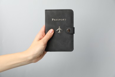 Photo of Woman holding passport in bright cover on grey background, closeup