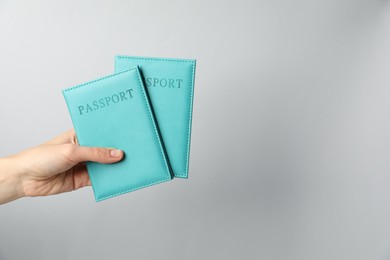 Photo of Woman holding passports in bright covers on grey background, closeup. Space for text