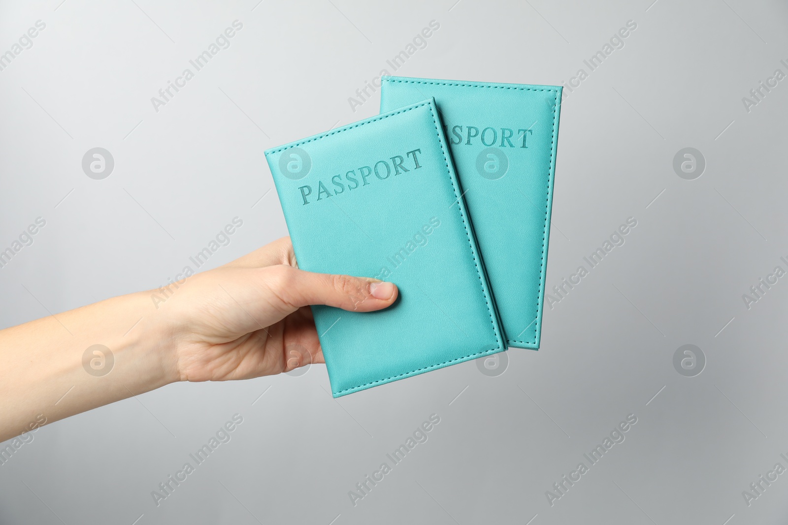 Photo of Woman holding passports in bright covers on grey background, closeup