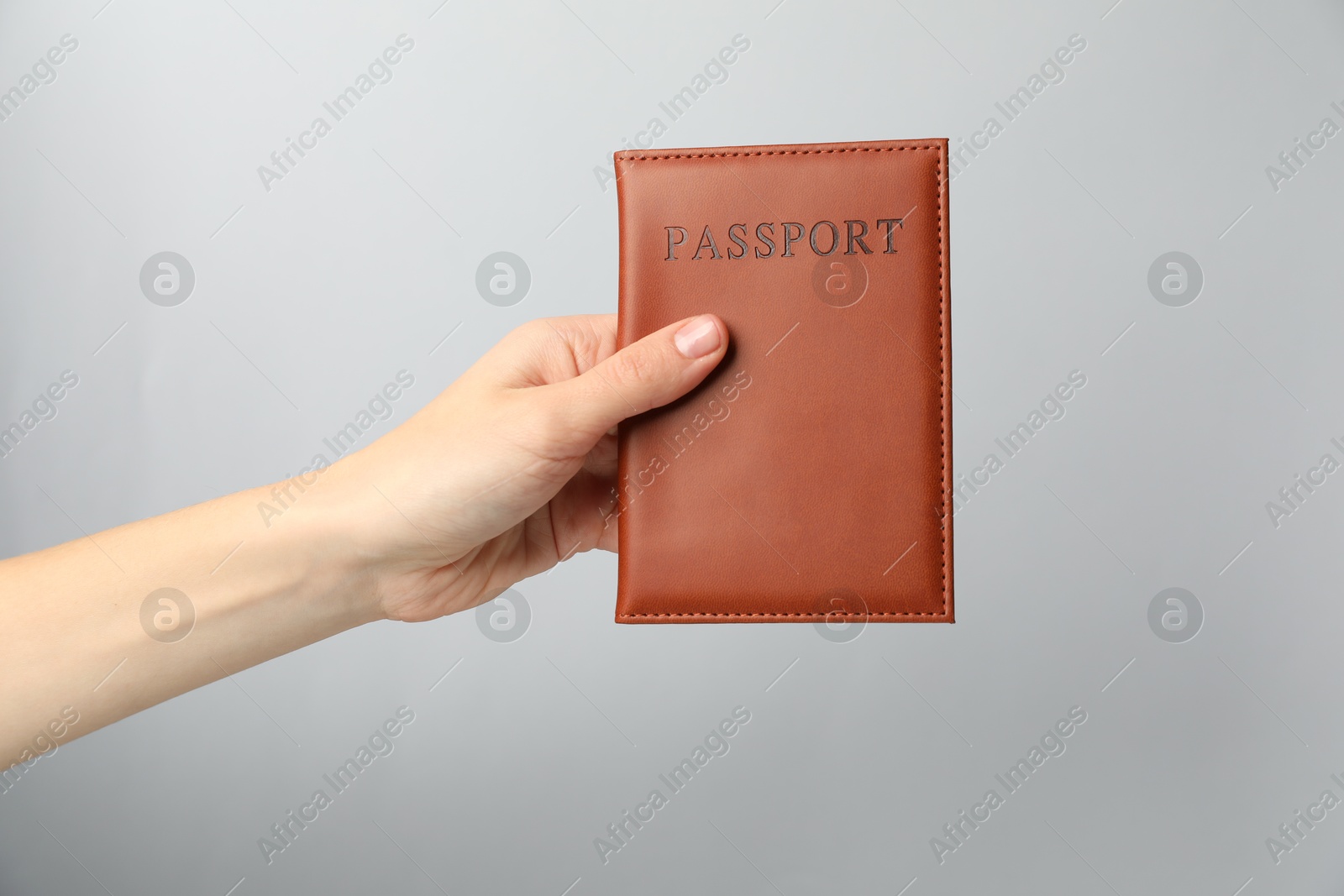 Photo of Woman holding passport in bright cover on grey background, closeup