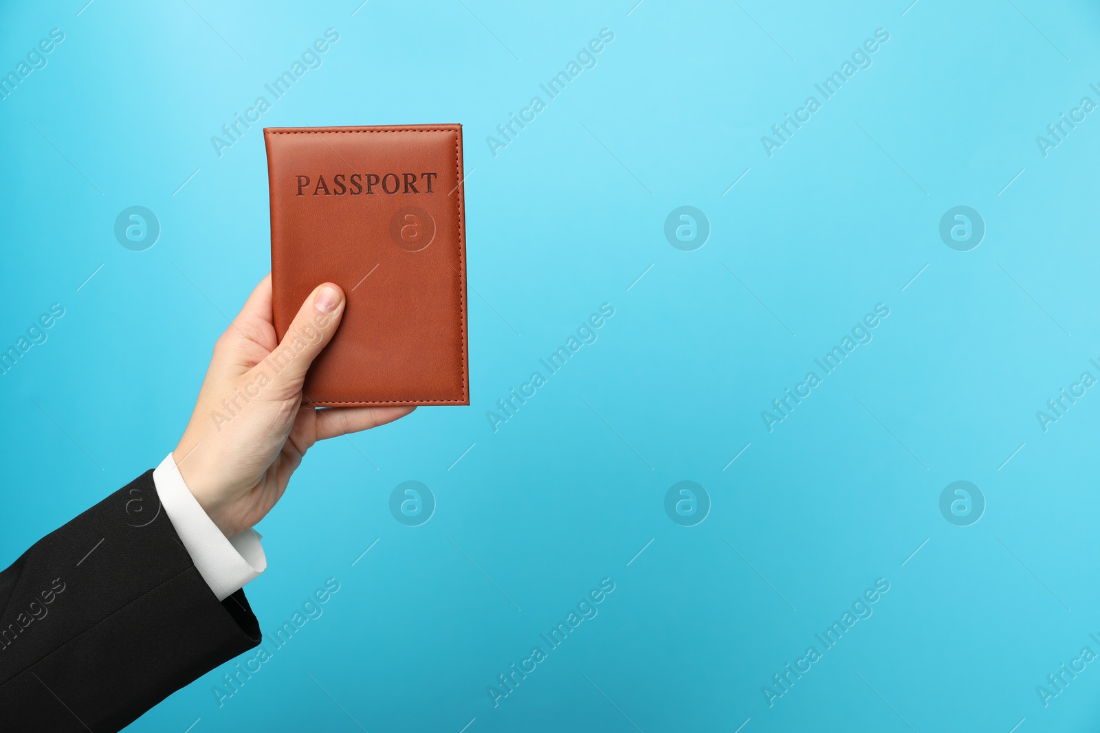 Photo of Woman holding passport in bright cover on light blue background, closeup. Space for text