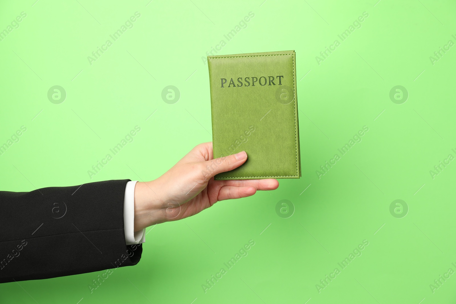 Photo of Woman holding passport in bright cover on green background, closeup