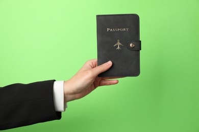 Photo of Woman holding passport in bright cover on green background, closeup