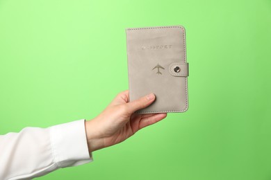 Photo of Woman holding passport in bright cover on green background, closeup