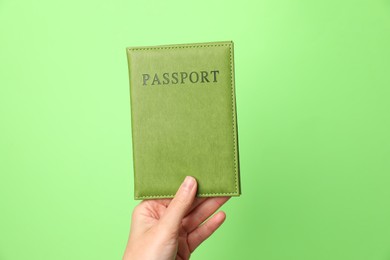 Photo of Woman holding passport in bright cover on green background, closeup