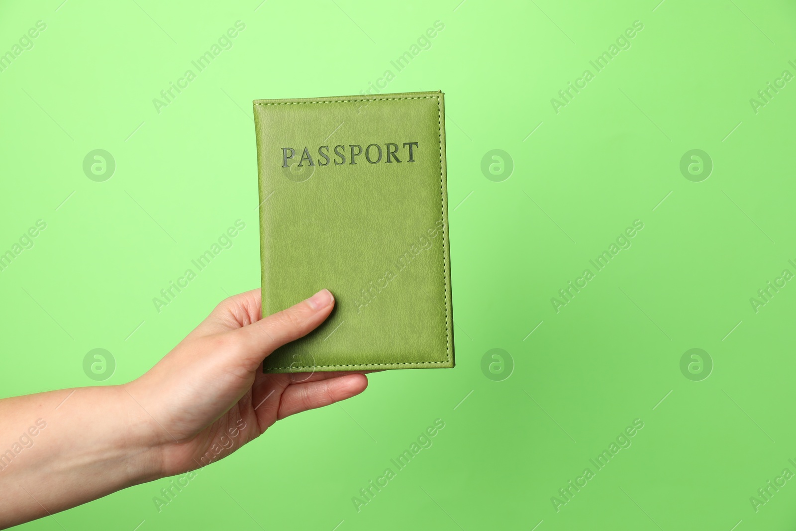 Photo of Woman holding passport in bright cover on green background, closeup. Space for text