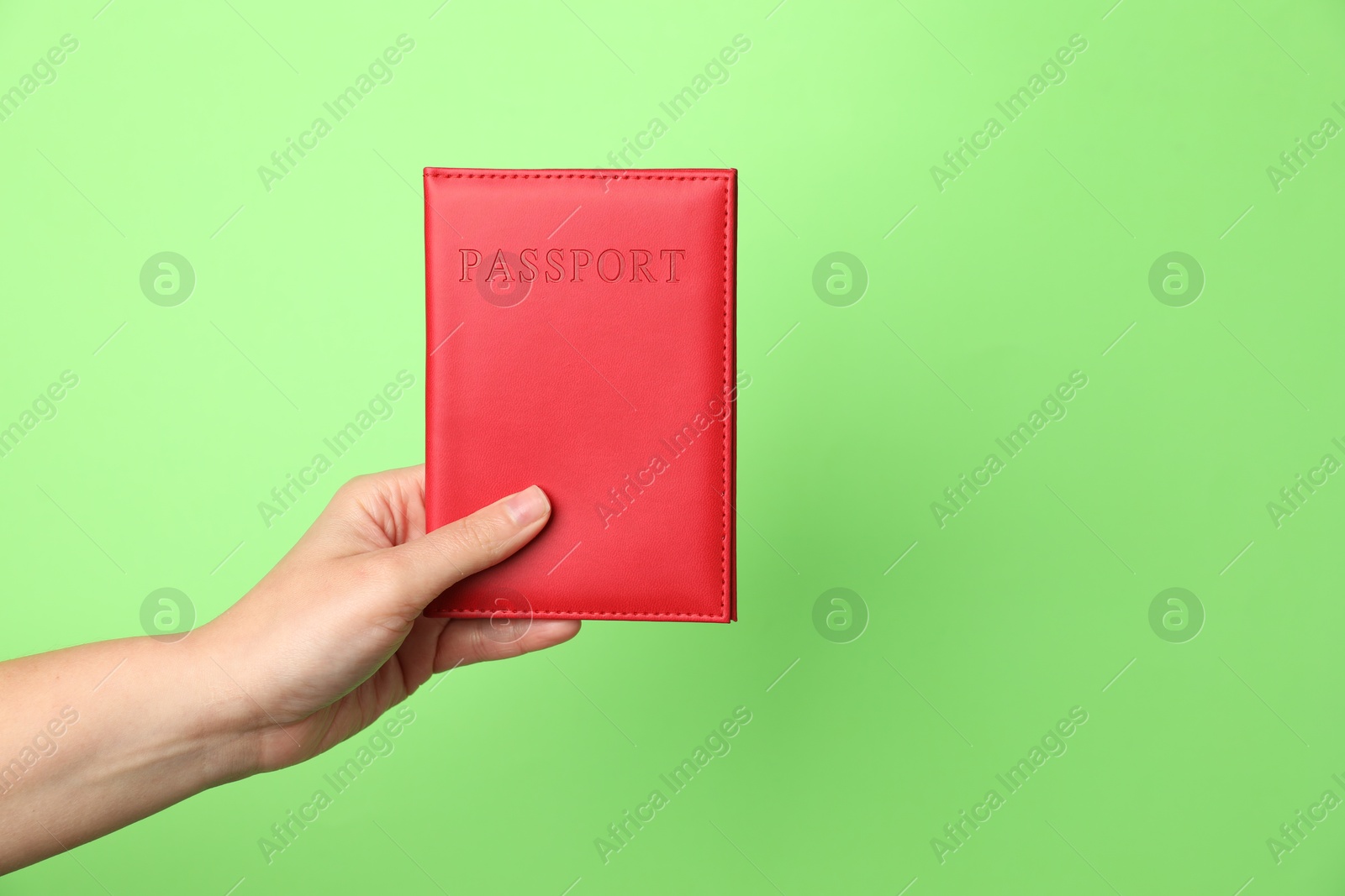 Photo of Woman holding passport in bright cover on green background, closeup. Space for text