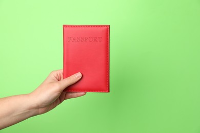 Photo of Woman holding passport in bright cover on green background, closeup. Space for text