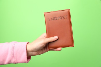 Photo of Woman holding passport in bright cover on green background, closeup