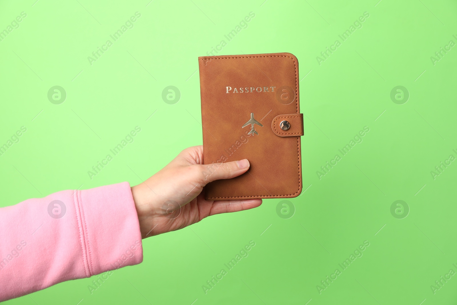 Photo of Woman holding passport in bright cover on green background, closeup