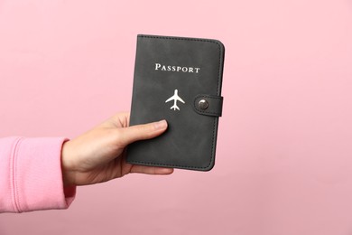 Photo of Woman holding passport in bright cover on pink background, closeup