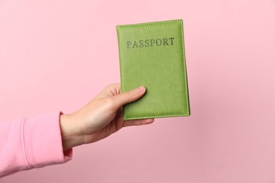 Photo of Woman holding passport in bright cover on pink background, closeup