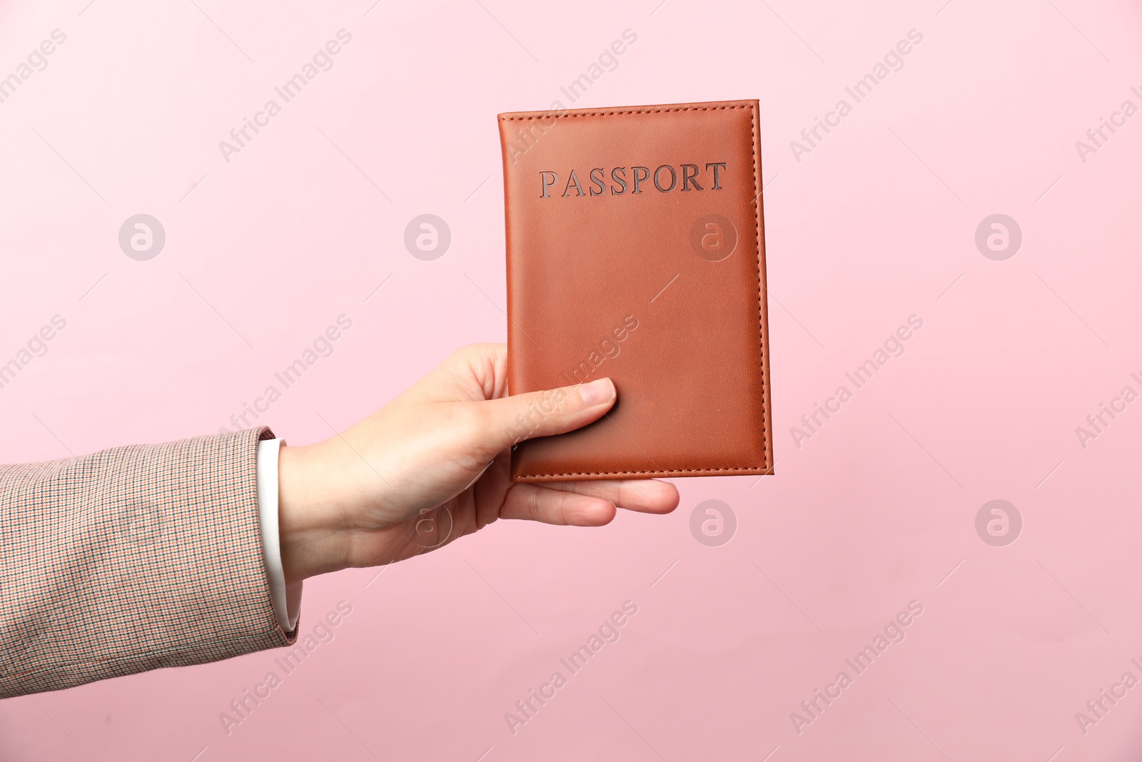 Photo of Woman holding passport in bright cover on pink background, closeup