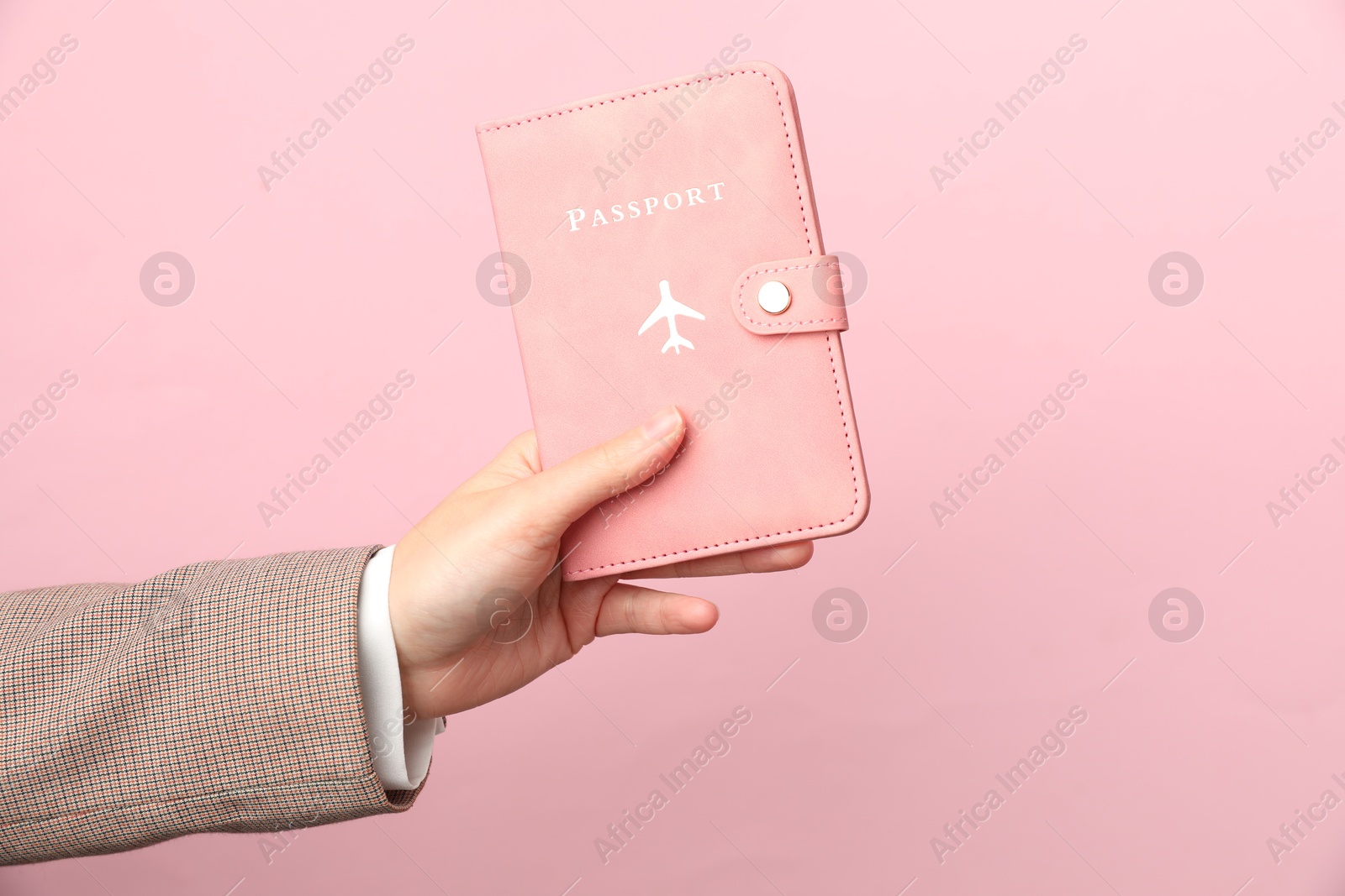 Photo of Woman holding passport in bright cover on pink background, closeup