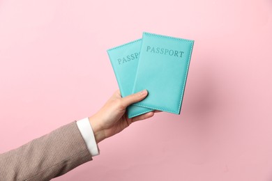 Photo of Woman holding passports in bright covers on pink background, closeup