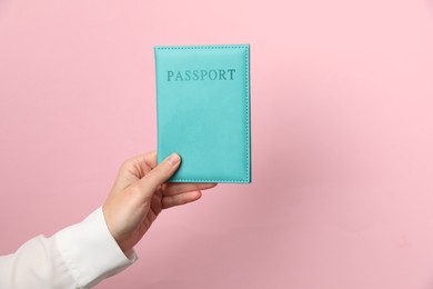 Photo of Woman holding passport in bright cover on pink background, closeup. Space for text