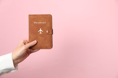 Photo of Woman holding passport in bright cover on pink background, closeup. Space for text