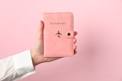 Photo of Woman holding passport in bright cover on pink background, closeup