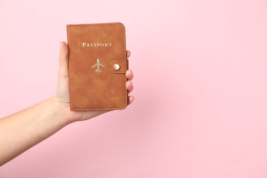 Photo of Woman holding passport in bright cover on pink background, closeup. Space for text