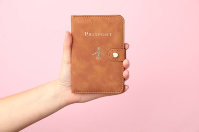 Photo of Woman holding passport in bright cover on pink background, closeup