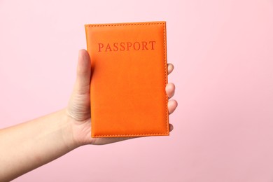 Photo of Woman holding passport in bright cover on pink background, closeup