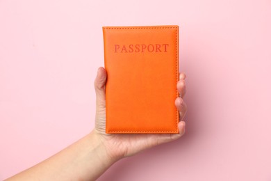 Photo of Woman holding passport in bright cover on pink background, closeup