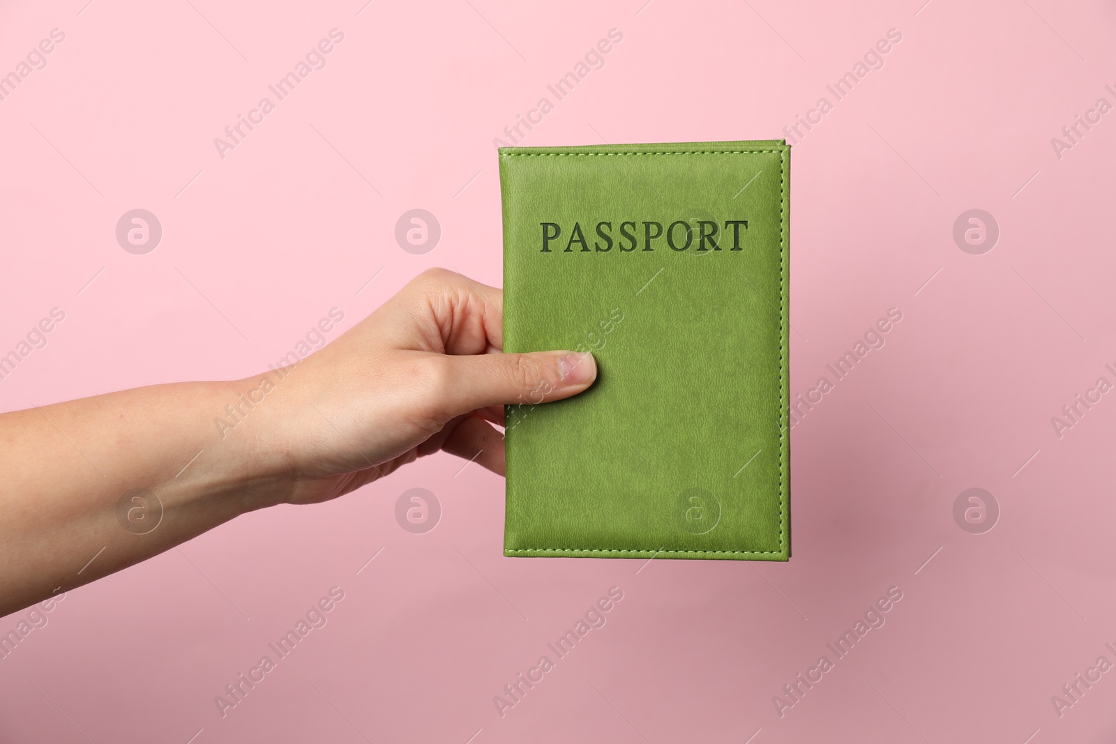 Photo of Woman holding passport in bright cover on pink background, closeup