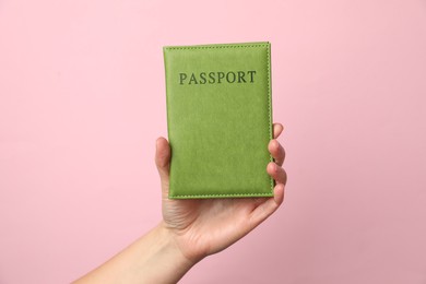 Photo of Woman holding passport in bright cover on pink background, closeup