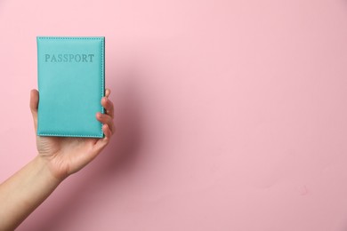 Photo of Woman holding passport in bright cover on pink background, closeup. Space for text