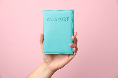 Photo of Woman holding passport in bright cover on pink background, closeup