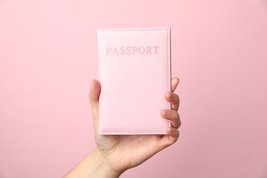 Photo of Woman holding passport in bright cover on pink background, closeup