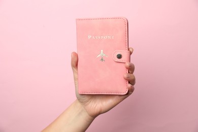 Photo of Woman holding passport in bright cover on pink background, closeup