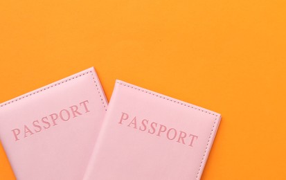 Photo of Passports in bright covers on orange background, top view. Space for text