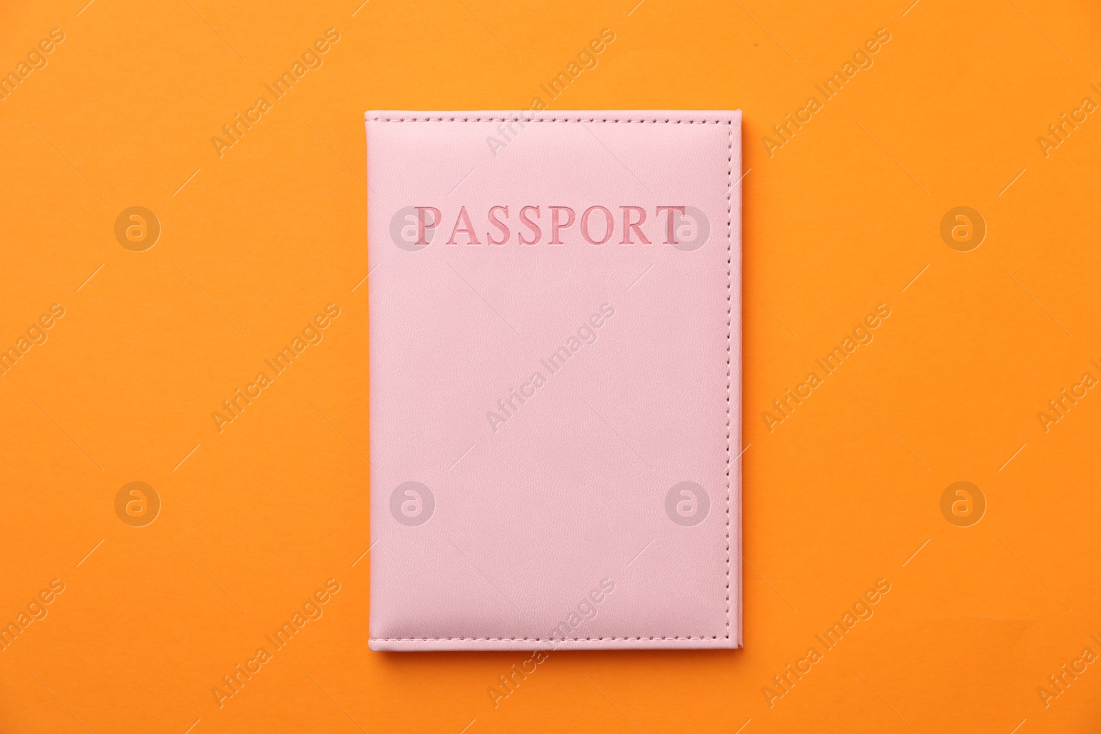 Photo of Passport in bright cover on orange background, top view