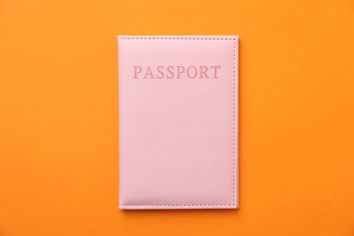 Photo of Passport in bright cover on orange background, top view