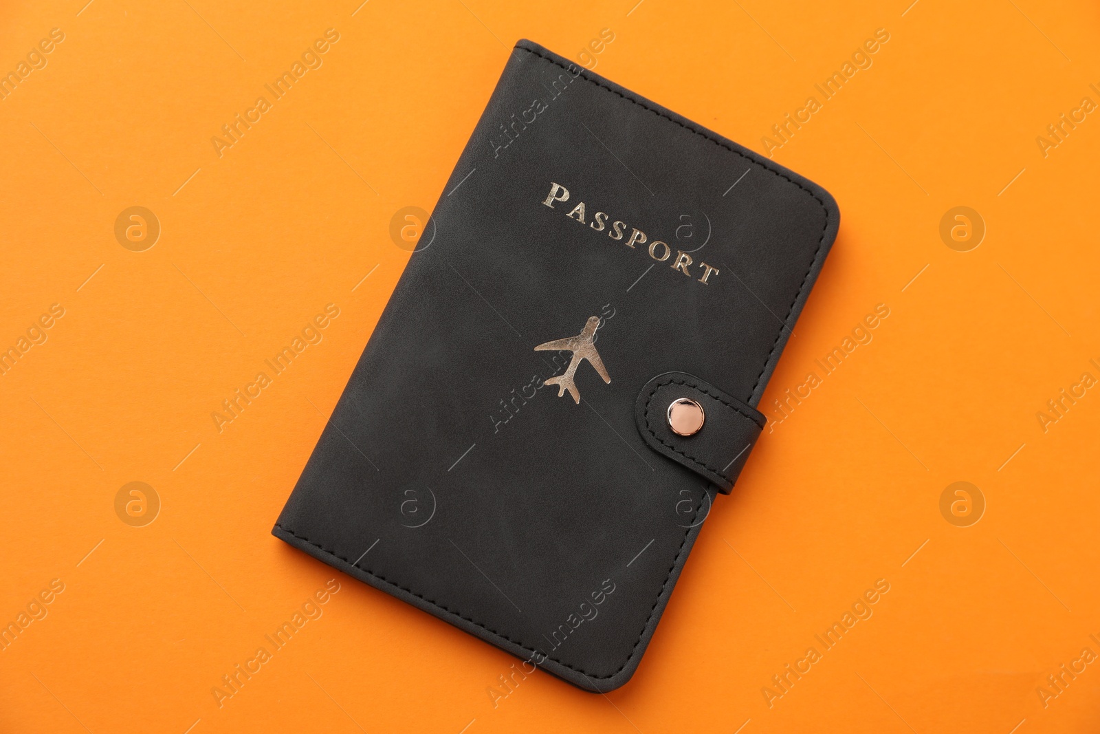 Photo of Passport in bright cover on orange background, top view