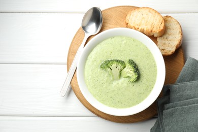 Photo of Delicious broccoli cream soup served on white wooden table, top view. Space for text