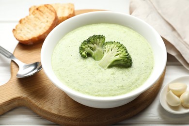 Photo of Delicious broccoli cream soup served on white wooden table, closeup