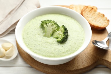 Photo of Delicious broccoli cream soup served on white wooden table, closeup