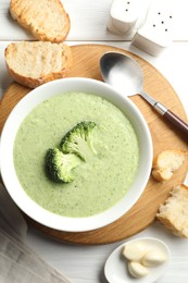 Photo of Delicious broccoli cream soup served on white wooden table, flat lay