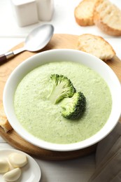 Photo of Delicious broccoli cream soup served on white wooden table, closeup