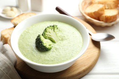 Photo of Delicious broccoli cream soup served on white wooden table, closeup