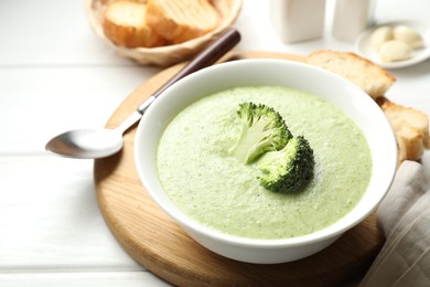 Photo of Delicious broccoli cream soup served on white wooden table, closeup