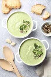 Photo of Delicious broccoli cream soup served on light table, flat lay