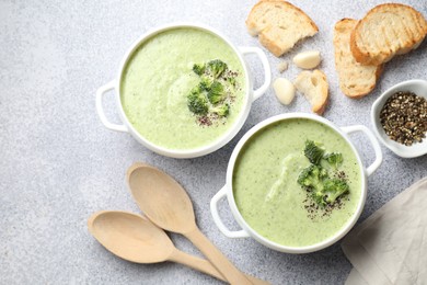 Photo of Delicious broccoli cream soup served on light table, flat lay