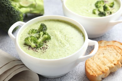 Photo of Delicious broccoli cream soup served on light table, closeup