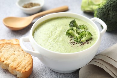 Photo of Delicious broccoli cream soup served on light table, closeup