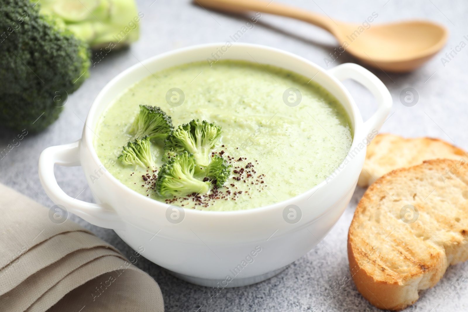 Photo of Delicious broccoli cream soup served on light table, closeup