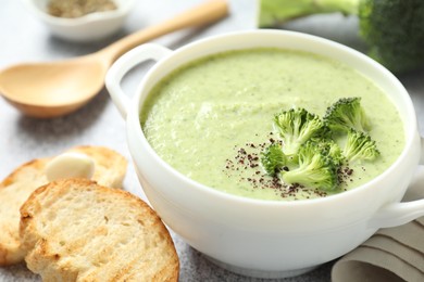 Photo of Delicious broccoli cream soup served on light table, closeup